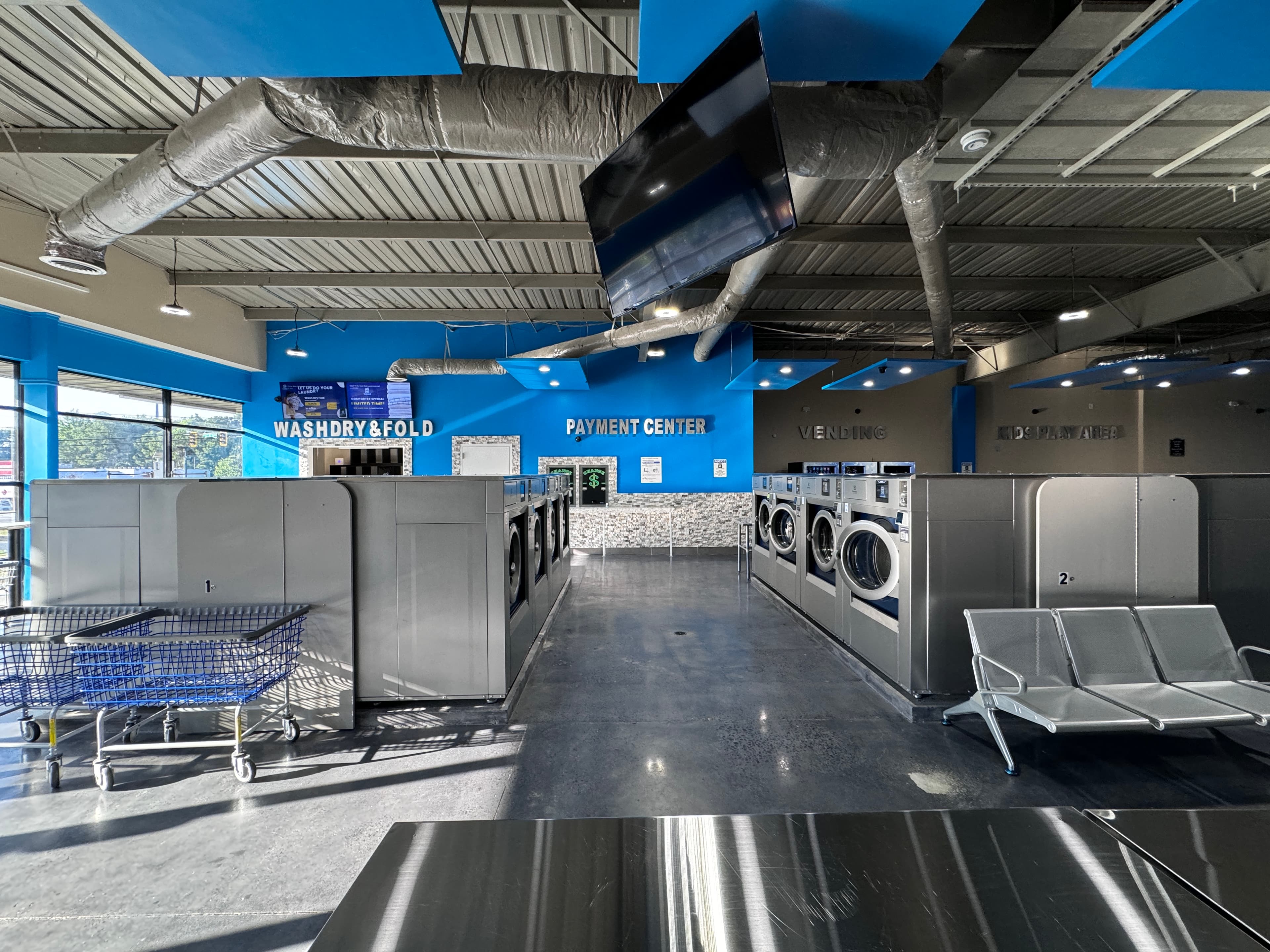 Modern stainless steel washers inside WashLuxe Laundry